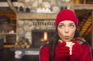 woman in red holding warm mug fireplace background
