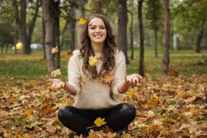 woman sitting on ground with fall leaves