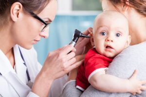 Doctor examining baby boy with otoscope