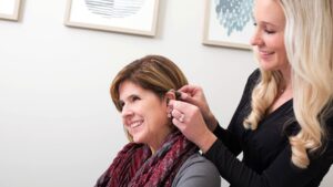 Dr. Lisa Bragg Putting a Hearing Aid on for a Patient